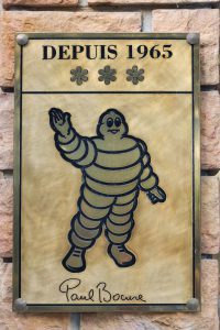 Lyon, France - September 25, 2015: Paul Bocuse paneloof 3 stars at the Michelin guide on the facade at the entrance of the restaurant. Paul Bocuse is a french chef based in Lyon who is famous for the high quality of his restaurant.