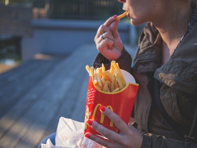 Kvinna som äter pommes frites